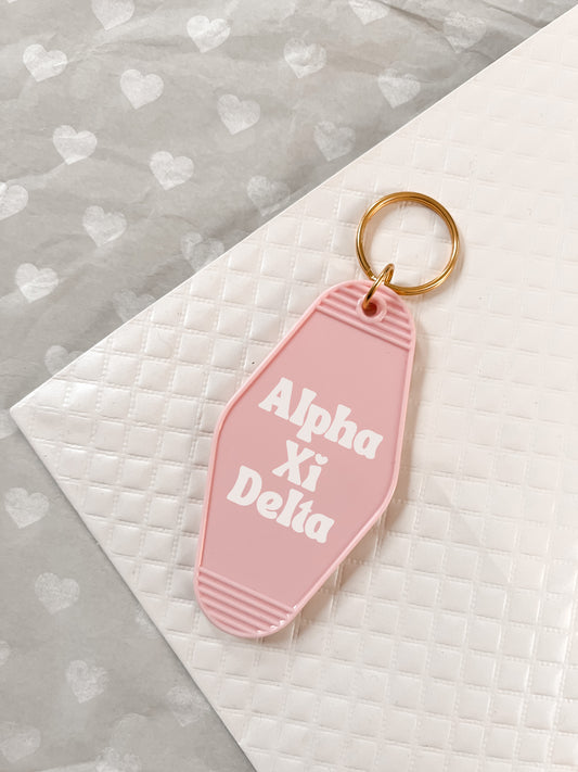 Alpha Xi Delta Motel Hotel Key Chain in Soft pink with white letters and gold ring. AXiD AXD