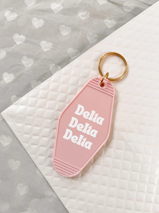 Delta Delta Delta Motel Hotel Key Chain in Soft pink with white letters and gold ring. TriDelta